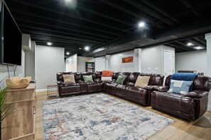 A modern living room with a sectional sofa, a large rug, and a flat-screen TV.