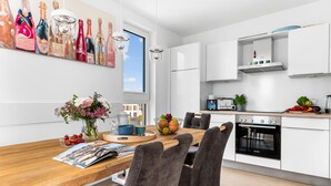 Una cucina moderna con mobili bianchi, un forno Bosch e un'area pranzo con tavolo e sedie in legno.