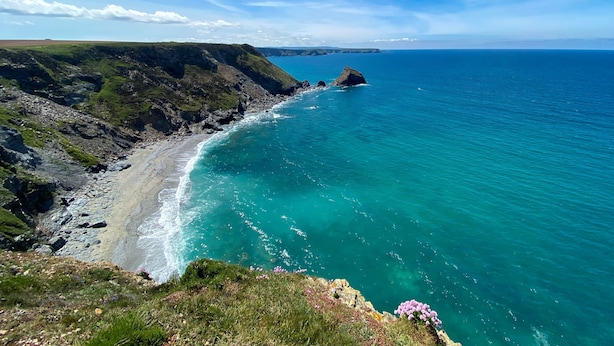 Paisaje costero con un litoral rocoso, mar azul cristalino y accidentes geográficos a la distancia.