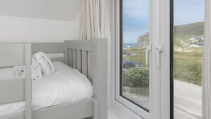 Una cama individual con ropa de cama blanca en una habitación con un amplio ventanal.