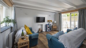 A living room with a fireplace, a television, and a bookshelf. - Sublimely located in the thriving village of St Agnes, just a stone's throw from the beauty of Cornw (St Agnes)