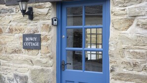 A stone cottage with a blue door and a sign reading "BOWJY COTTAGE". - Sublimely located in the thriving village of St Agnes, just a stone's throw from the beauty of Cornw (St Agnes)