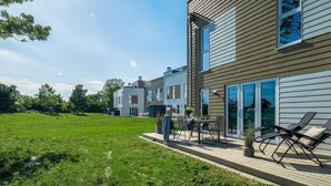 Un immeuble résidentiel moderne doté d’un vaste patio extérieur, de grandes fenêtres et d’une pelouse bien entretenue.