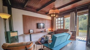 Een gezellige woonkamer met een blauwe bank, een houten plafond, een televisie en een open haard.