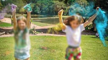Dos niños jugando en un área verde con árboles al fondo.
