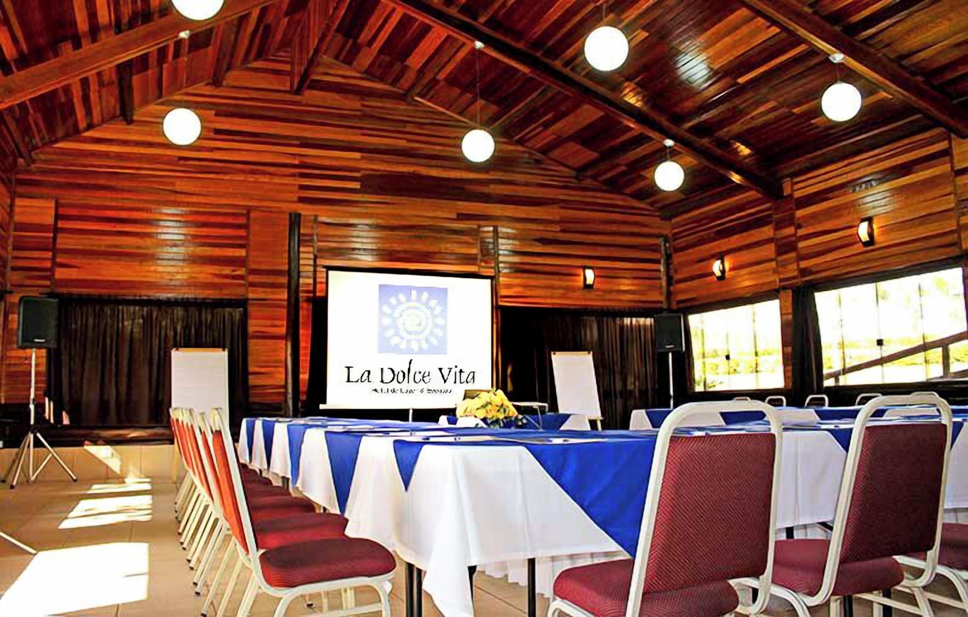 A conference room with a stage, a projection screen, and rows of chairs.