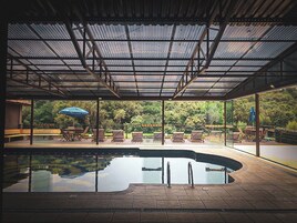 Una piscina techada con vistas a un jardín exuberante y árboles.
