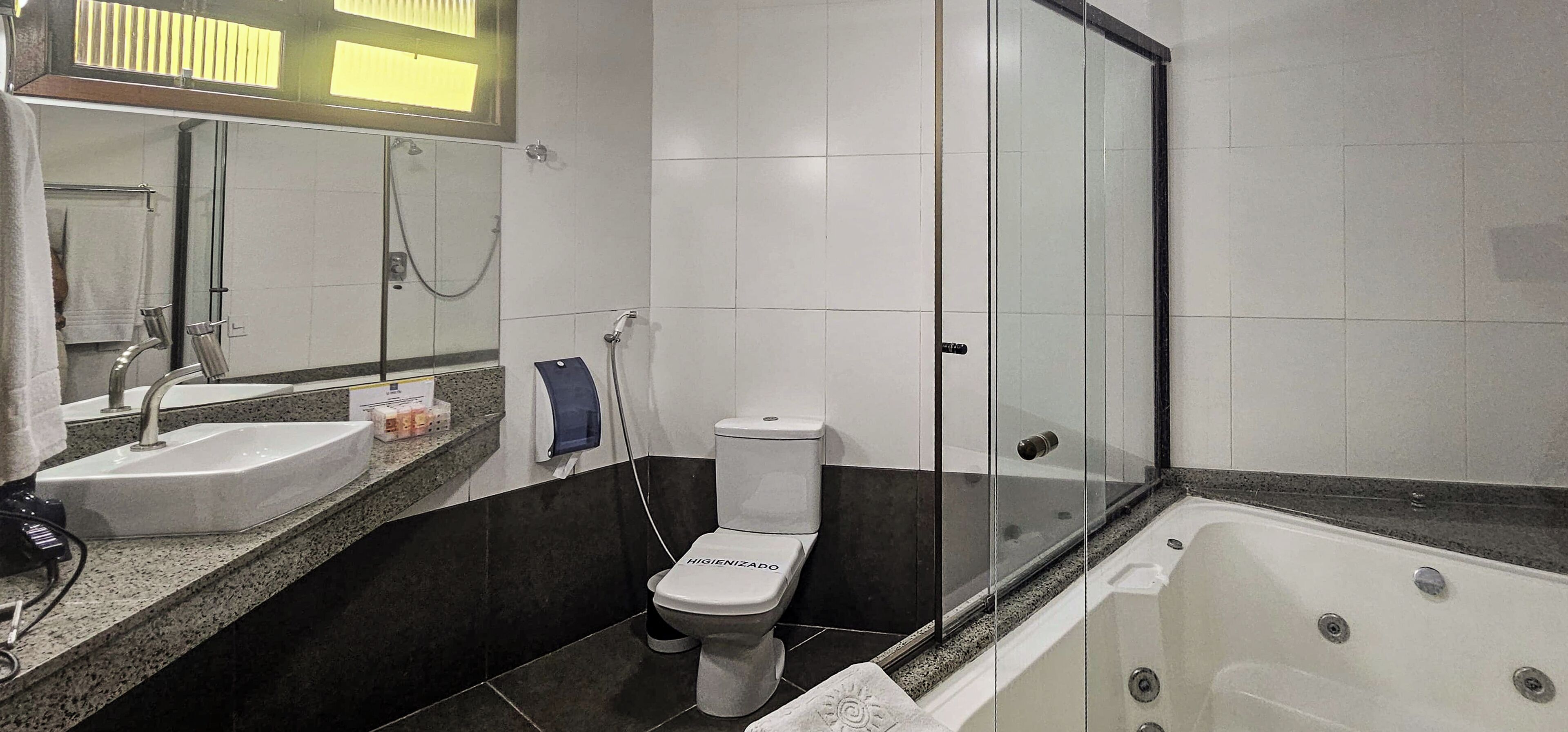 Um banheiro com pia branca, vaso sanitário, banheira e chuveiro com box de vidro.