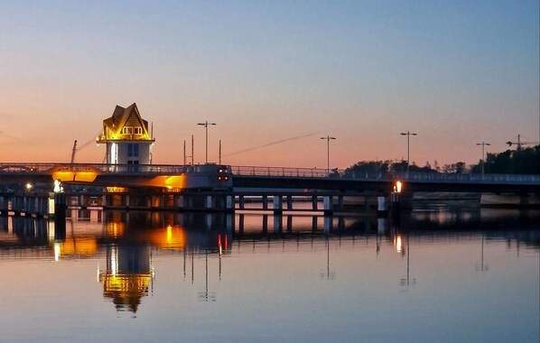 Un pont surmonté d’un phare à son extrémité, enjambant une étendue d’eau calme.