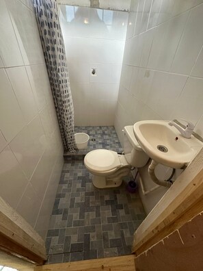 A small bathroom with a toilet, sink, and shower curtain. - Yaxlik River lodge (San Agustin Lanquin)