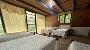 A room with four beds, wooden floors, and large windows with curtains. - Yaxlik River lodge (San Agustin Lanquin)