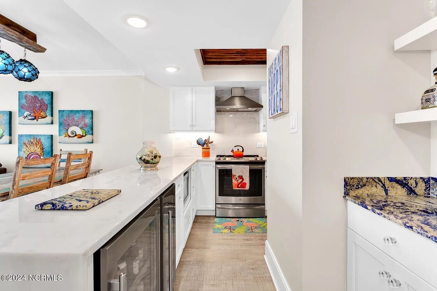 A modern kitchen with white cabinetry, a stainless steel range hood, and a tiled backsplash.