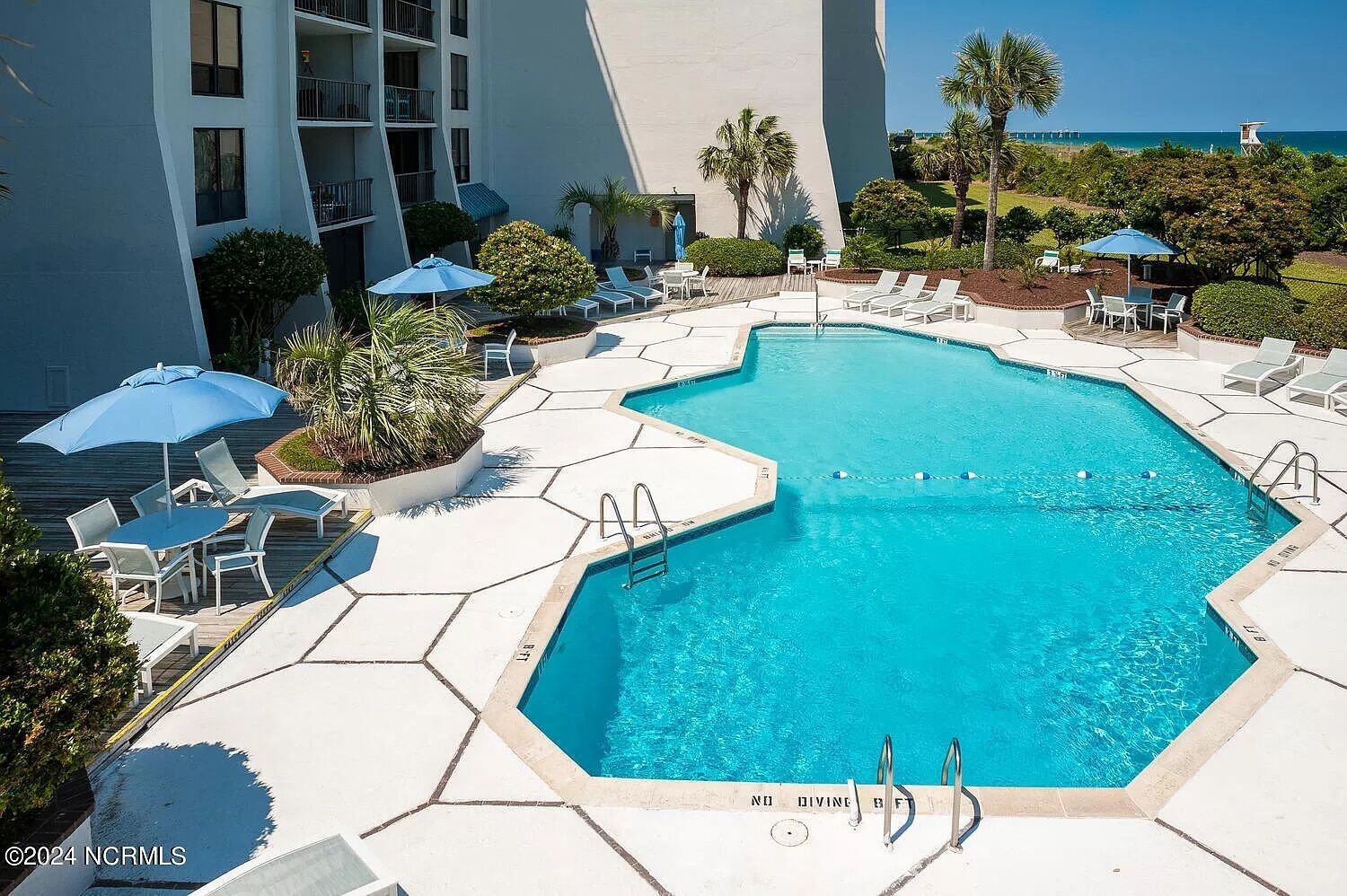 Un área de piscina con varias piscinas, sillas de descanso y sombrillas.