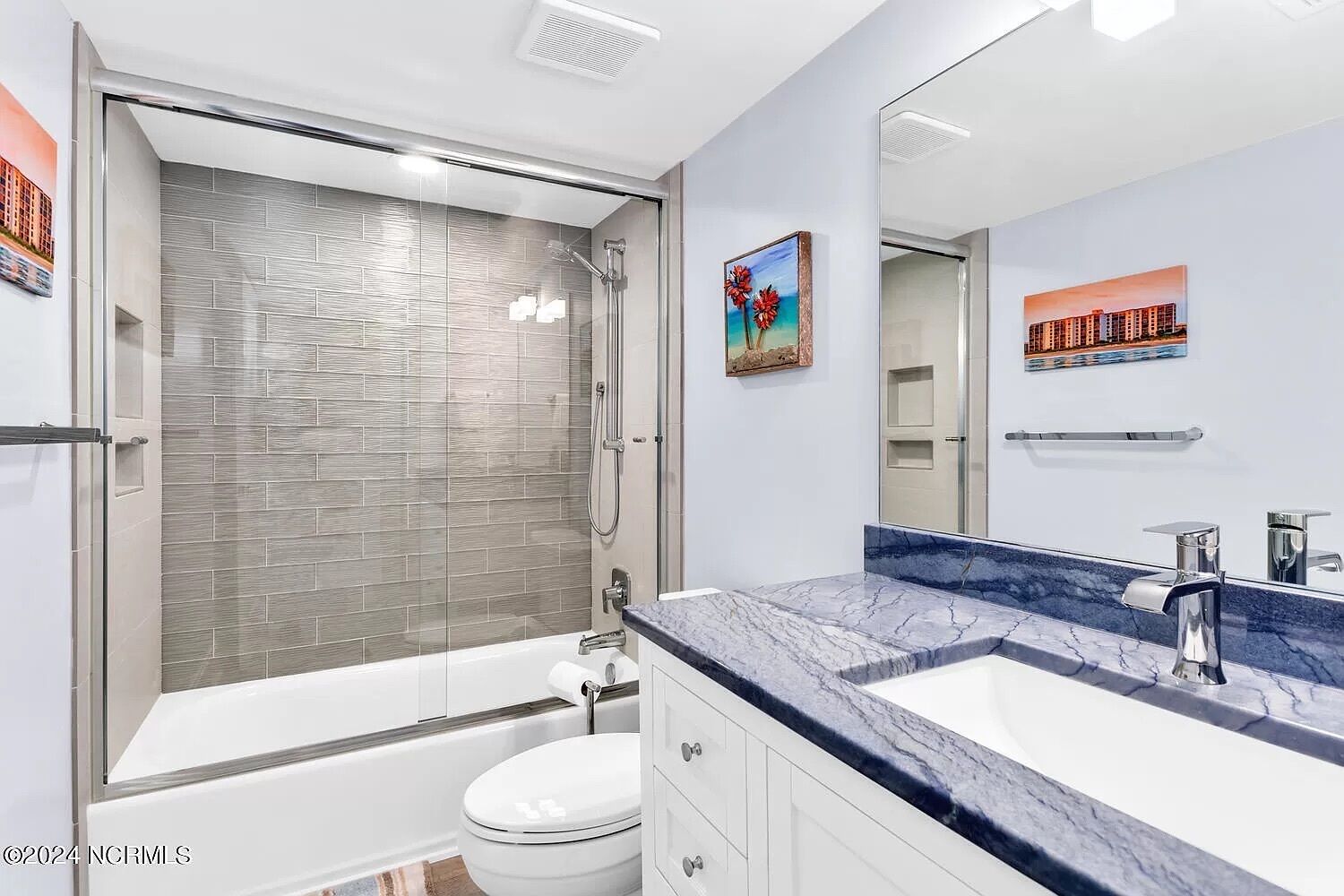 A modern bathroom with a glass-enclosed shower, a white toilet, and a marble countertop with a sink.
