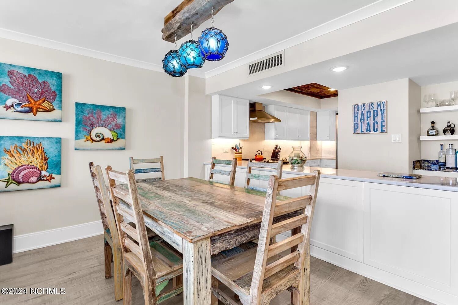 A dining area with a rustic wooden table and chairs, surrounded by wall art depicting sea life.