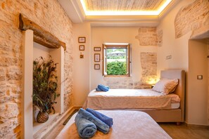 A bedroom with two beds, a peacock plant, and a window with a view of greenery. - Charming Villa in Agnitsini, Corfu – Pool, WiFi, Aircon (Agnitsini)