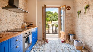 Une cuisine avec des meubles de couleur bleue, une cuisinière et une grande fenêtre.