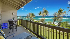 Ein Balkon mit Blick auf das Meer, ausgestattet mit einem Tisch, Stühlen und einem blauen Koffer.