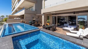 A rooftop pool area with multiple swimming pools, outdoor seating, and a modern building structure. - Luxury condo with pool, jacuzzi and private terrace (Cabo San Lucas)