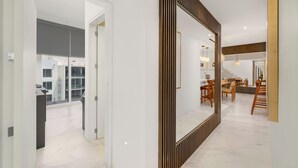A modern interior with a large mirror, a dining area, and a view of the outside. - Stunning Penthouse with Private Terrace & Jacuzzi Views (Cabo San Lucas)