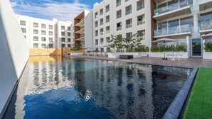 A modern hotel with a swimming pool, outdoor seating, and a well-maintained garden. - Stunning Penthouse with Private Terrace & Jacuzzi Views (Cabo San Lucas)