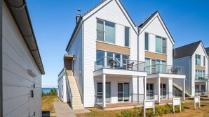 A modern two-story house with a balcony, a wooden deck, and a view of the sea. - Stunning apartment in Olpenitz (Olpenitz)