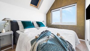 A bedroom with a bed, a nightstand, a lamp, a window, and a skylight. - Stunning apartment in Olpenitz (Olpenitz)