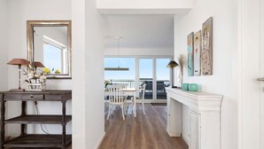 A hallway with a wooden floor, a white fireplace, and a dining area with a view to the outside. - Stunning apartment in Olpenitz (Olpenitz)