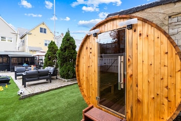 Escape to a tranquil backyard retreat with a wooden sauna and lush green space, ideal for a refreshing break.