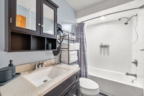 A modern bathroom with a large mirror, a sink, a toilet, and a shower.