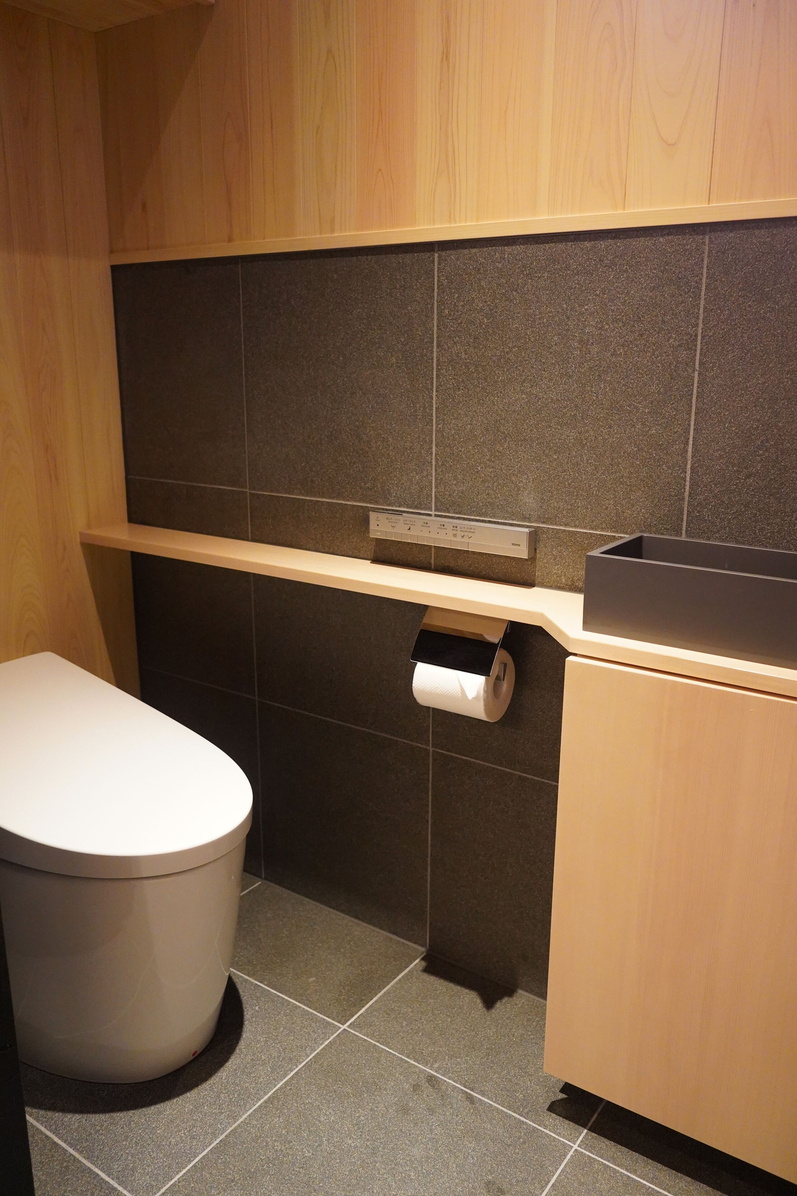 Ein kleines Badezimmer mit Toilette, Ablagefläche und Papierhandtuchspender.