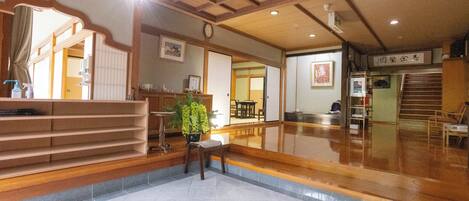 A spacious lobby with a wooden staircase, a reception desk, and a large mirror.