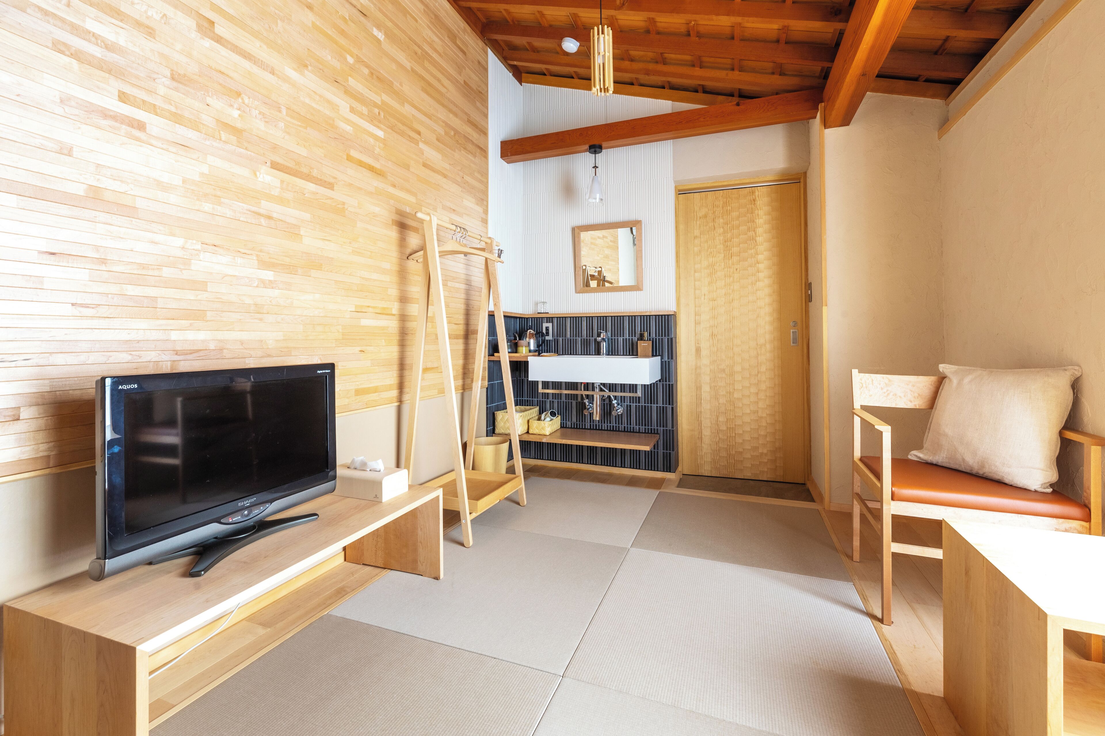 A traditional Japanese room with tatami flooring, a television on a wooden stand, a wooden ladder, and a sliding door.