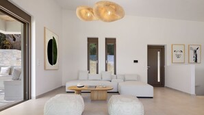 A modern living room with a sectional sofa, two poufs, a wooden coffee table, and a large abstract painting. - Villa Eptanisa in Sivota (Lefkada)