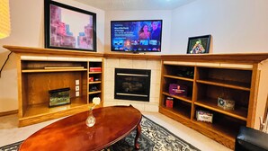 A living room with a fireplace, a TV mounted on the wall, and a coffee table.