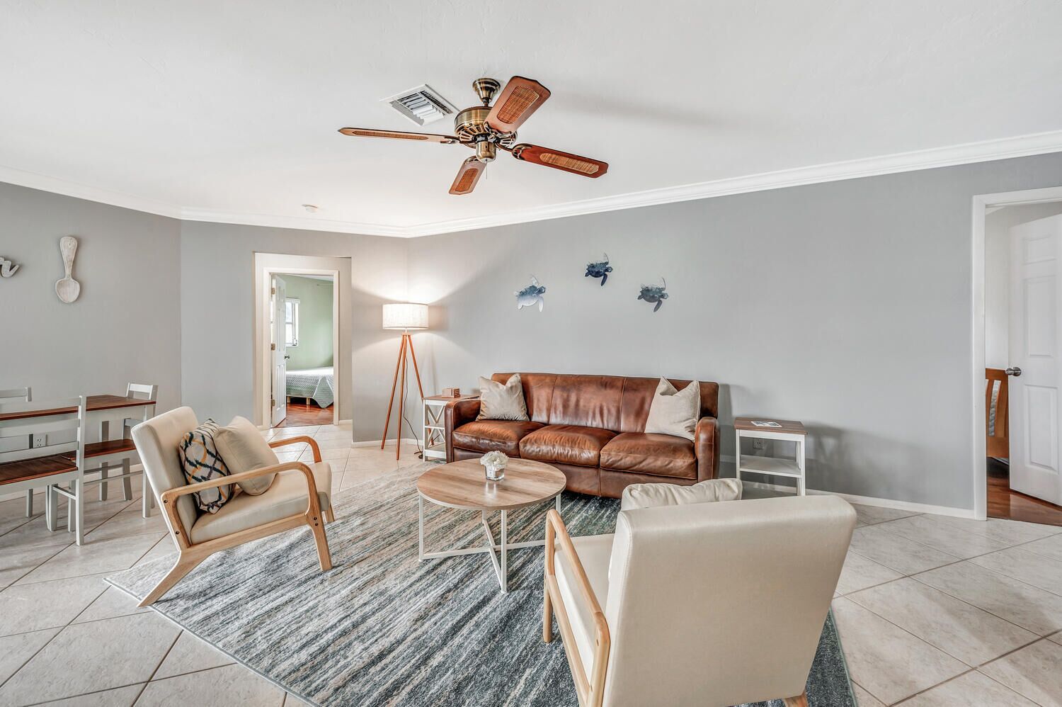 Un salon moderne avec un canapé en cuir marron, une table basse en bois et un ventilateur de plafond.