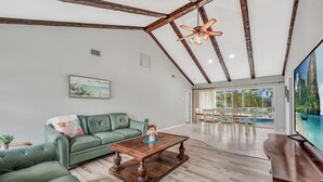 Amplia sala de estar con un sofá verde, una mesa de centro de madera y un ventilador de techo.
