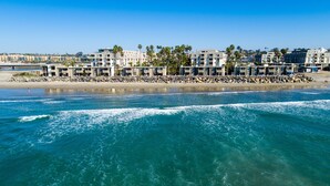 A coastal hotel with multiple buildings, a rocky shoreline, and clear blue waters.