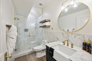 A modern bathroom with a glass-enclosed shower, a white toilet, a marble sink, and a large mirror with a gold frame. - Modern New 1-bedroom Guest House for 3 or Combined with Main House for 9 people  (Houston)