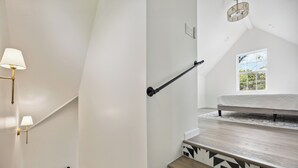 Una escalera con piso de diseño geométrico, barandilla y aplique de pared.