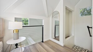 Un interior moderno con una escalera, una mesa redonda con una lámpara y una vista a través de un arco.