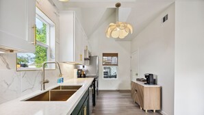 Una cocina moderna con una isla grande, electrodomésticos integrados y una lámpara colgante.