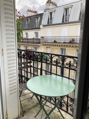 Enjoy the charming view from this balcony with a table and door, surrounded by a wrought iron railing with intricate designs.