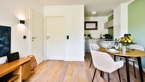 A modern kitchen with white cabinets, a dining table set for four, and a kitchen island. - Lille, Wenningstedt-braderup auf Sylt, Deutschland (Wenningstedt-Braderup (Sylt))