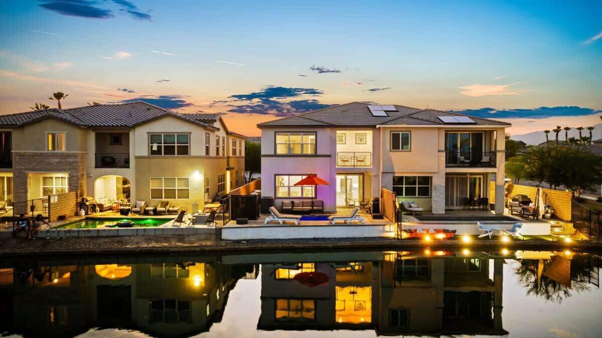 Un complesso residenziale con diverse abitazioni, una piscina e un riflesso nell'acqua.