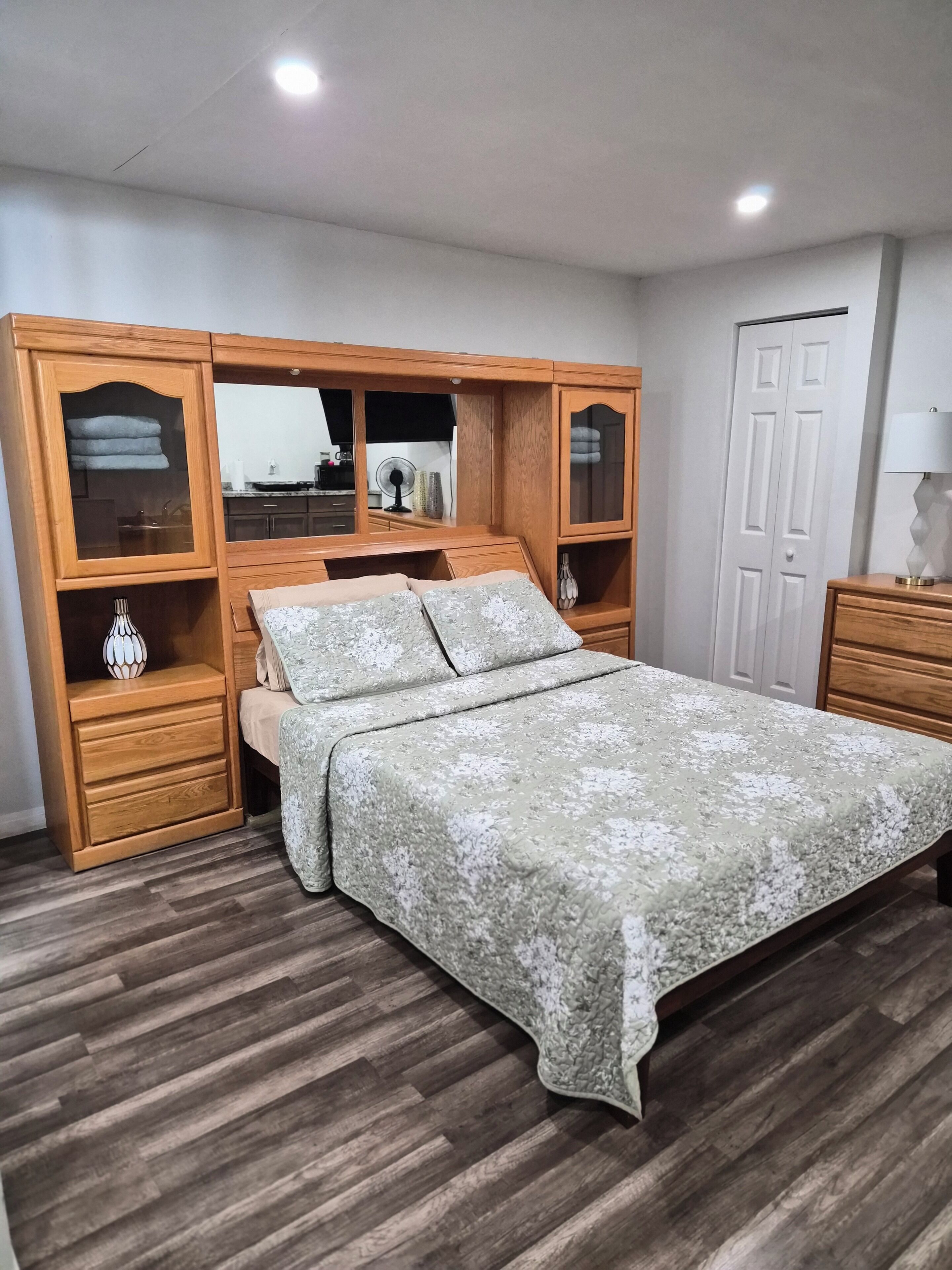 Una camera da letto con un letto, un armadio in legno e uno specchio.
