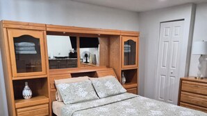 A bedroom with a bed, wooden wardrobe, and a mirror. - Private & Peaceful Suite | Fast WiFi | Patio | Close to Beaches & Downtown (Port Richey)
