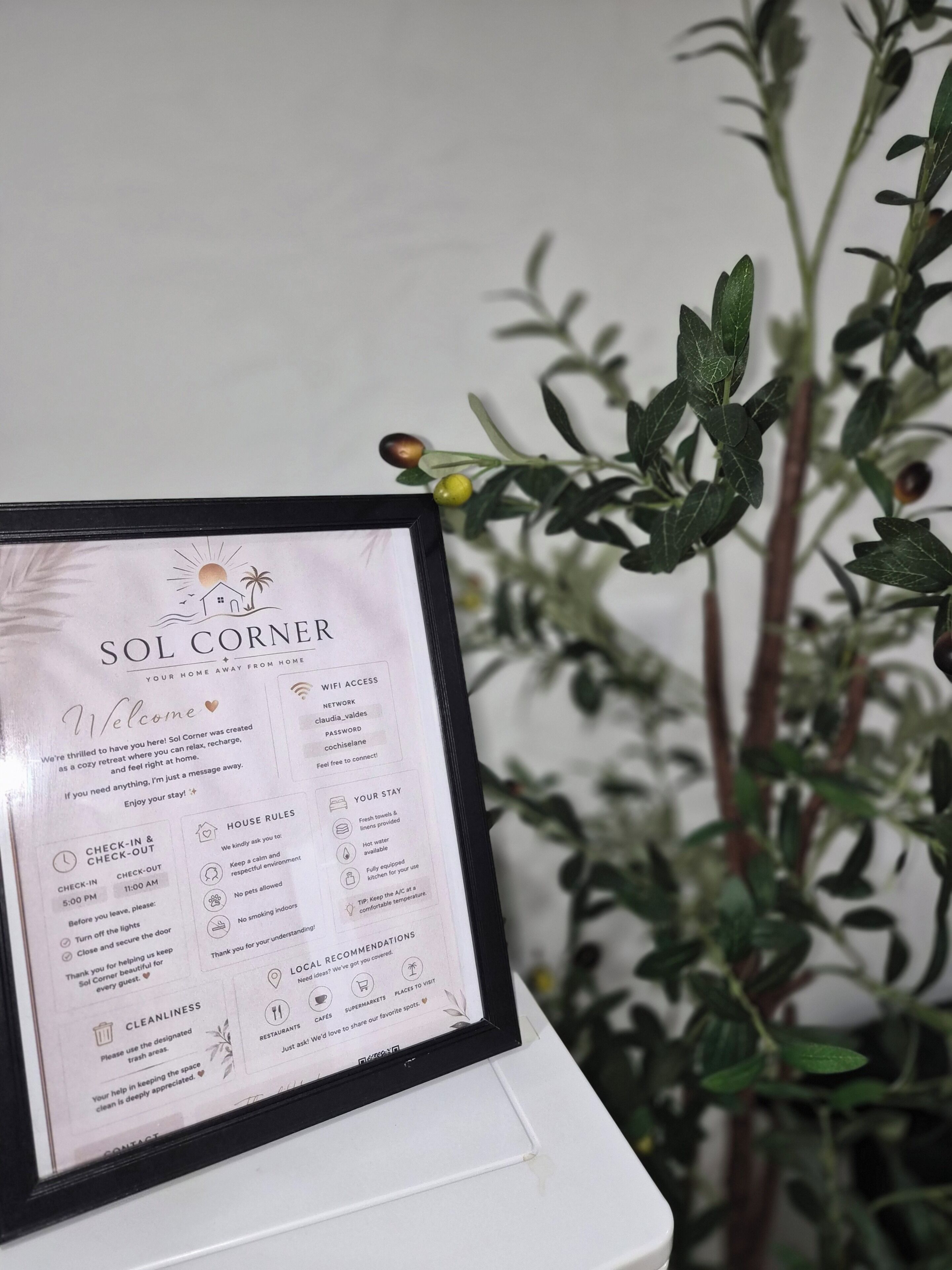 A framed welcome sign for Sol Corner, detailing amenities like WiFi, house rules, and local recommendations.