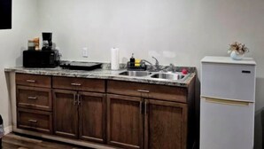 A kitchen with wooden cabinets, a granite countertop, a sink, a coffee maker, and a refrigerator. - Private & Peaceful Suite | Fast WiFi | Patio | Close to Beaches & Downtown (Port Richey)