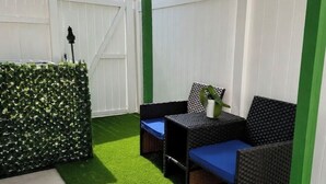 A patio area with artificial grass, a white fence, and outdoor furniture. - Private & Peaceful Suite | Fast WiFi | Patio | Close to Beaches & Downtown (Port Richey)